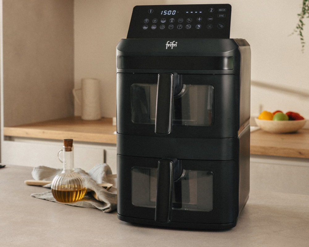 Friteuse à air chaud noire à double panier, dotée d'un panneau de commande numérique à écran tactile situé sur le dessus.