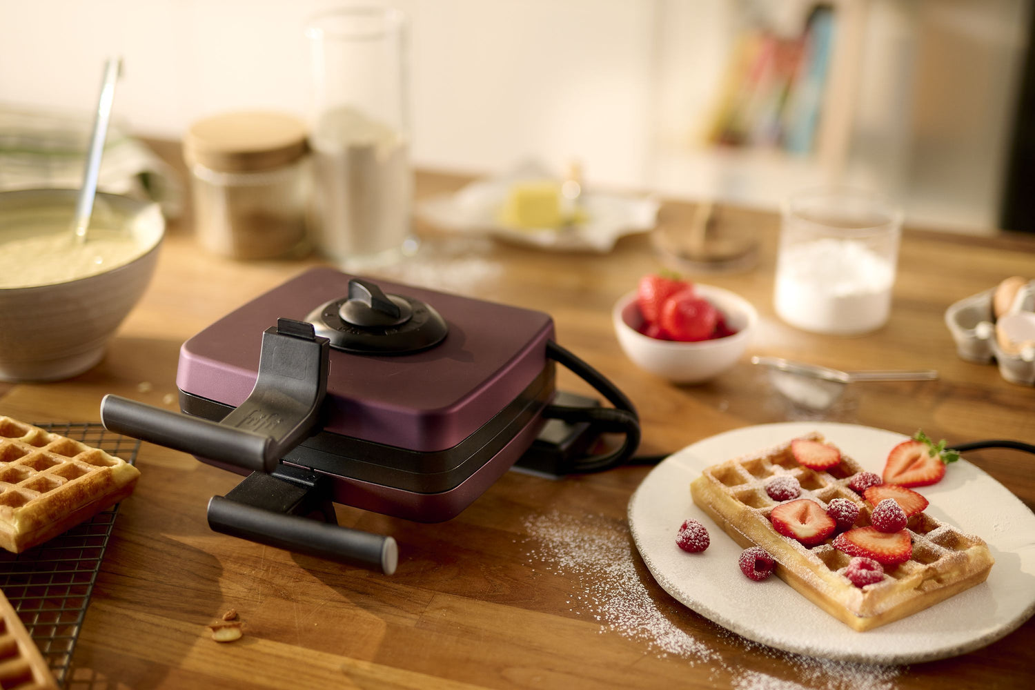 Gaufrier violet avec des gaufres décorées de fruits rouges et de sucre glace.
