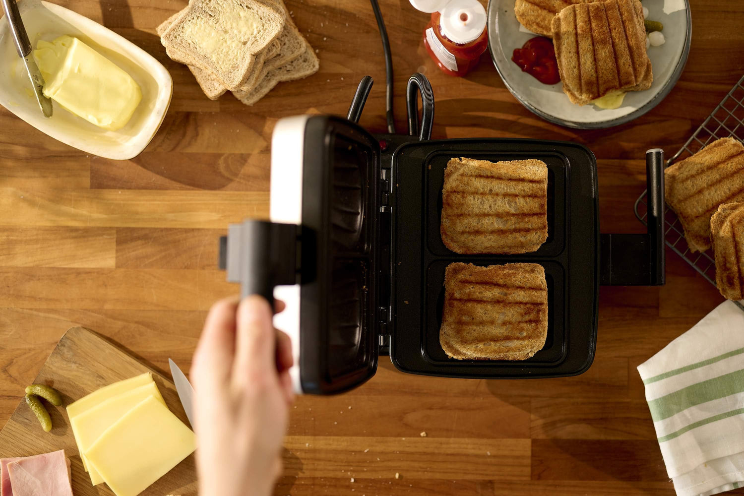 Grille-pain à sandwichs ouvert, pain grillé, beurre, ingrédients de garniture.