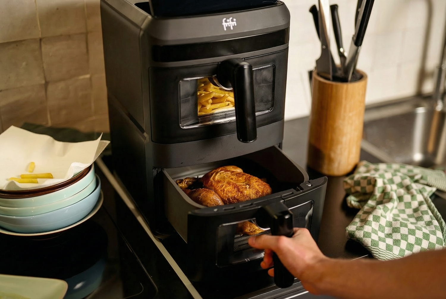 Quelqu'un prend une barquette de poulet rôti dans le compartiment inférieur de l'Airfryer Duo Slim (capacité XXL 13L) pendant que les frites cuisent dans le compartiment supérieur.