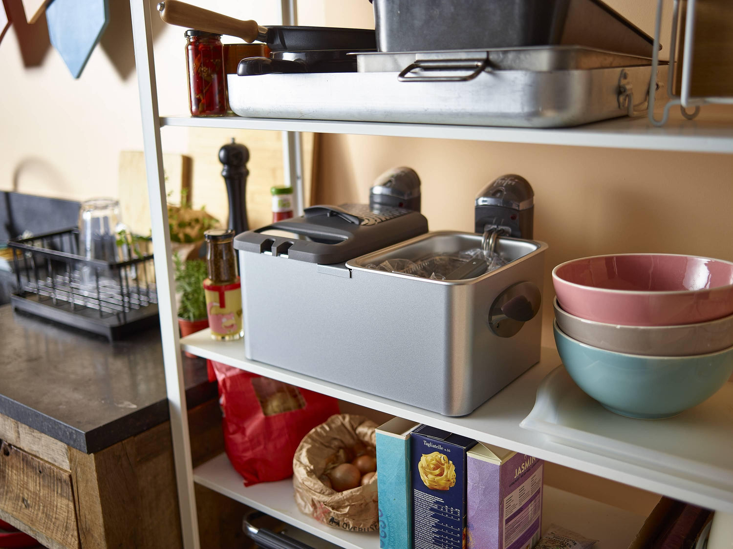 Étagère de cuisine avec friteuse et bols colorés.
