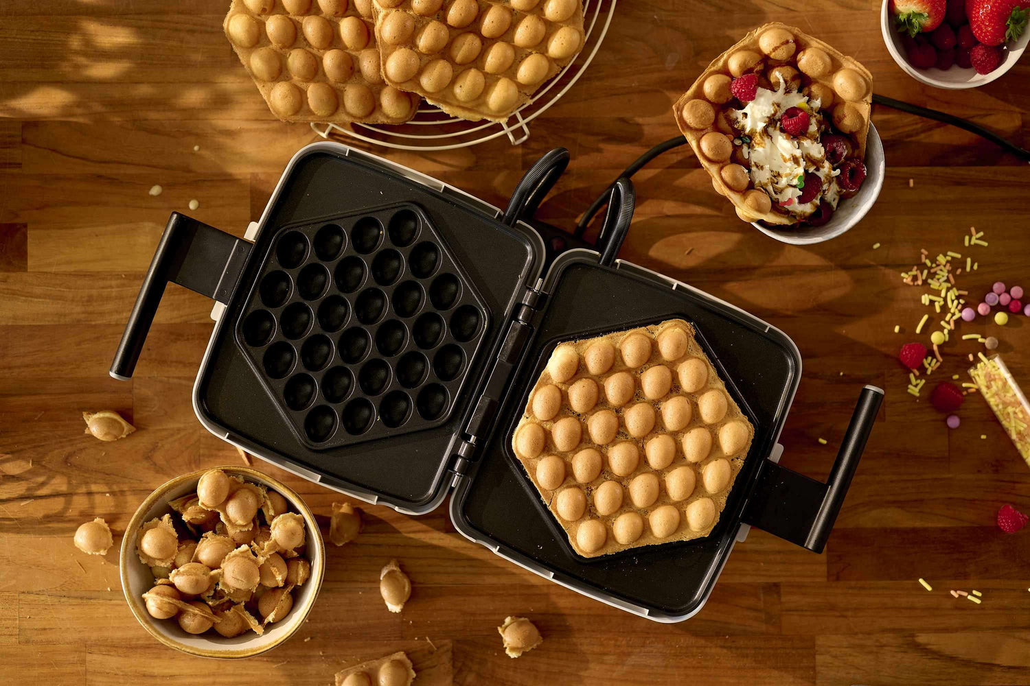 Gaufrier à bulles, gaufres, garnitures, table en bois.