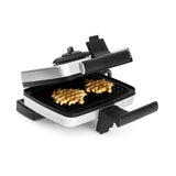 Gaufrier ouvert, en métal et plastique noir, avec deux gaufres cuites.